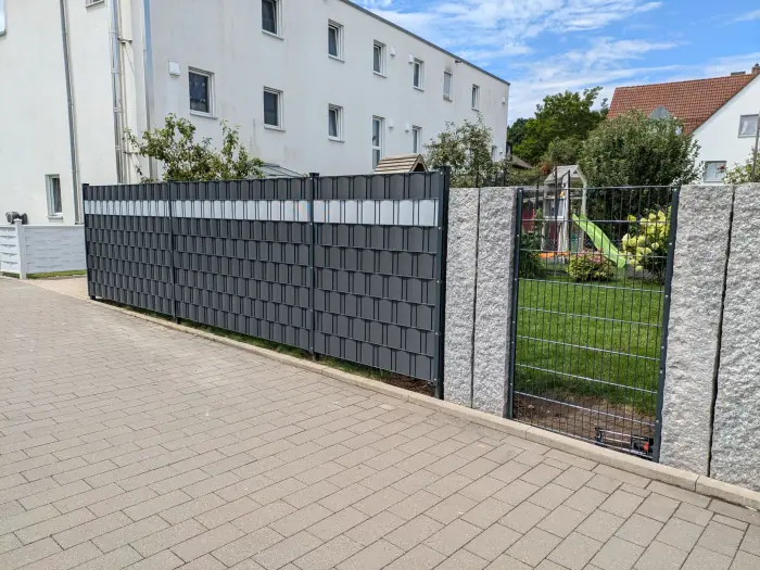 Doppelstabmattenzaun mit anthrazitfarbenen Sichtschutzstreifen an einer Einfahrt