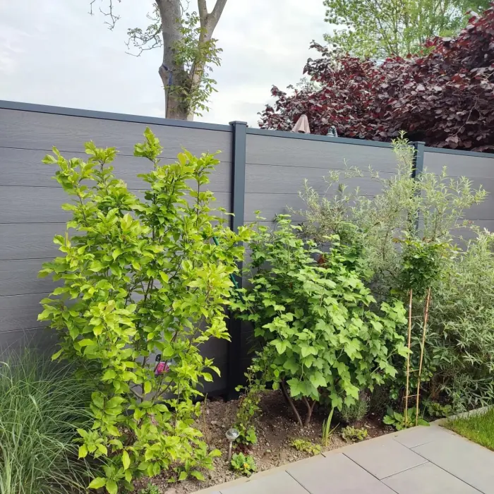 Grauer WPC-Sichtschutzzaun mit Beet im Garten